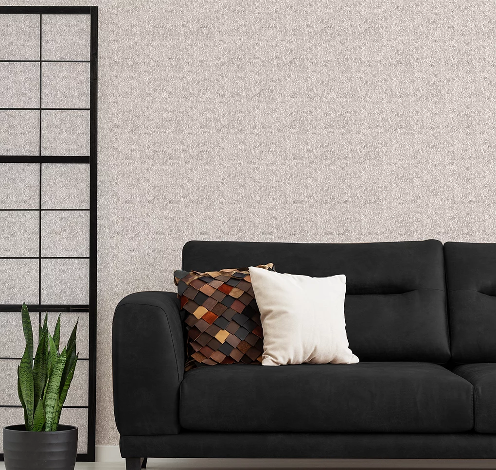 Giấy dán tường họa tiết thực vật màu xanh nhạt trong phòng khách với ghế sofa màu xanh nhạt, chăn đan màu xám và đệm nhung tròn.