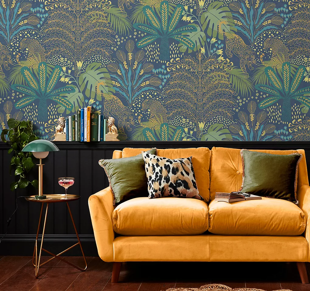 Giấy dán tường in hình lá xanh và vàng trong phòng có ghế bành màu nâu.