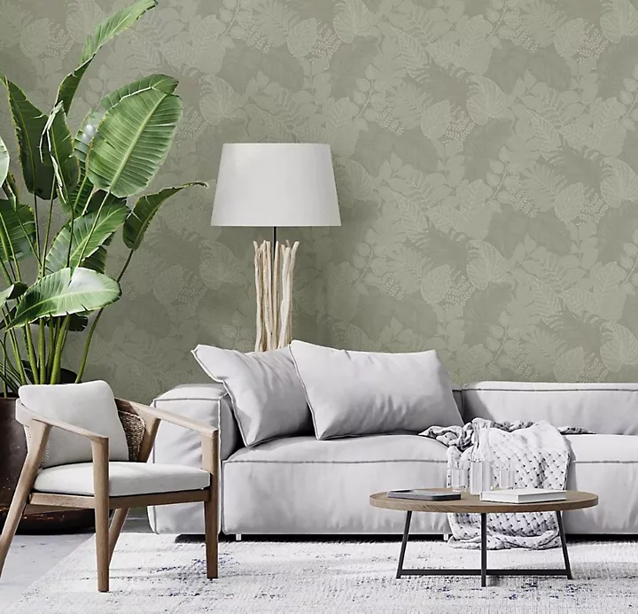 Giấy dán tường hình lá xanh trong phòng khách với ghế sofa màu xám và nhiều loại đệm nhung màu xanh lá cây, xanh lam và xám.