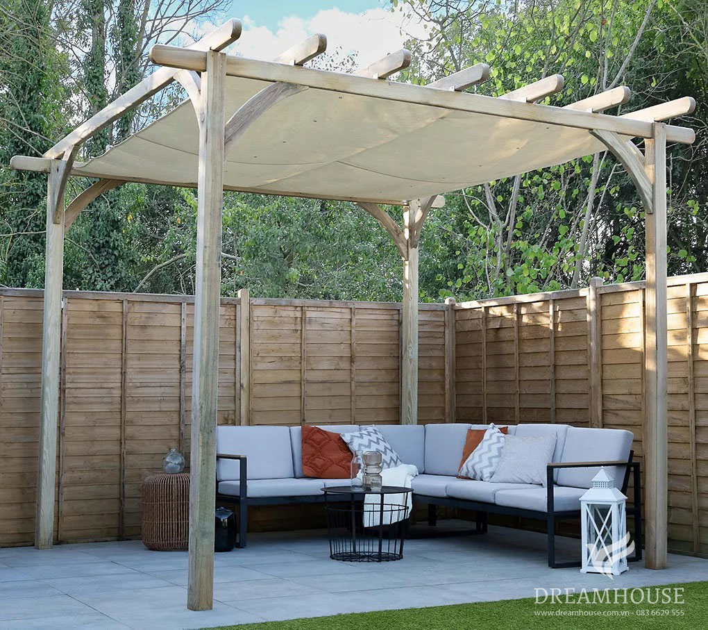 Giàn che bằng gỗ ở góc vườn, tạo bóng mát cho chiếc ghế sofa ngoài trời màu đen và xám sành điệu trong khu vực tiếp khách ấm cúng.