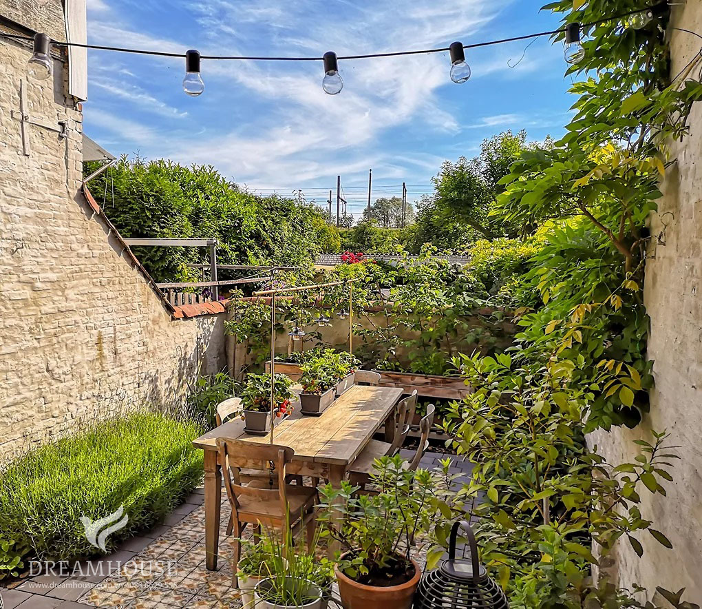 Khu vườn theo phong cách Địa Trung Hải với những chiếc chậu đất nung, đồ nội thất bằng gỗ mộc mạc và gạch nhiều màu sắc.