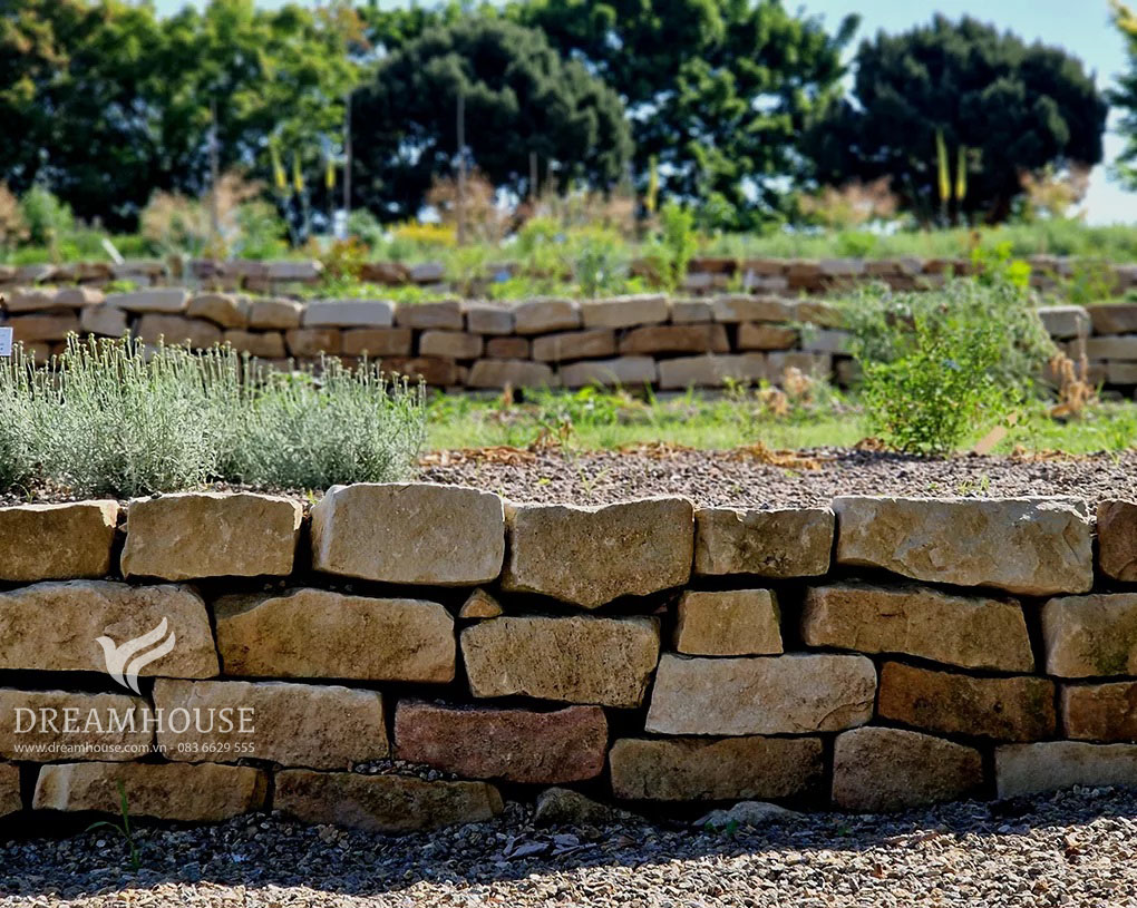 Khu vườn dốc được biến đổi bằng những bức tường đá thô sơ, tạo nên nhiều tầng và biến địa hình không bằng phẳng thành không gian ngoài trời tiện dụng và đẹp mắt.