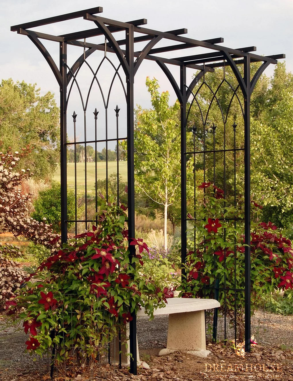Giàn cây kim loại đen quyến rũ được trang trí bằng những dây leo như cây kim ngân và hoa nhài.